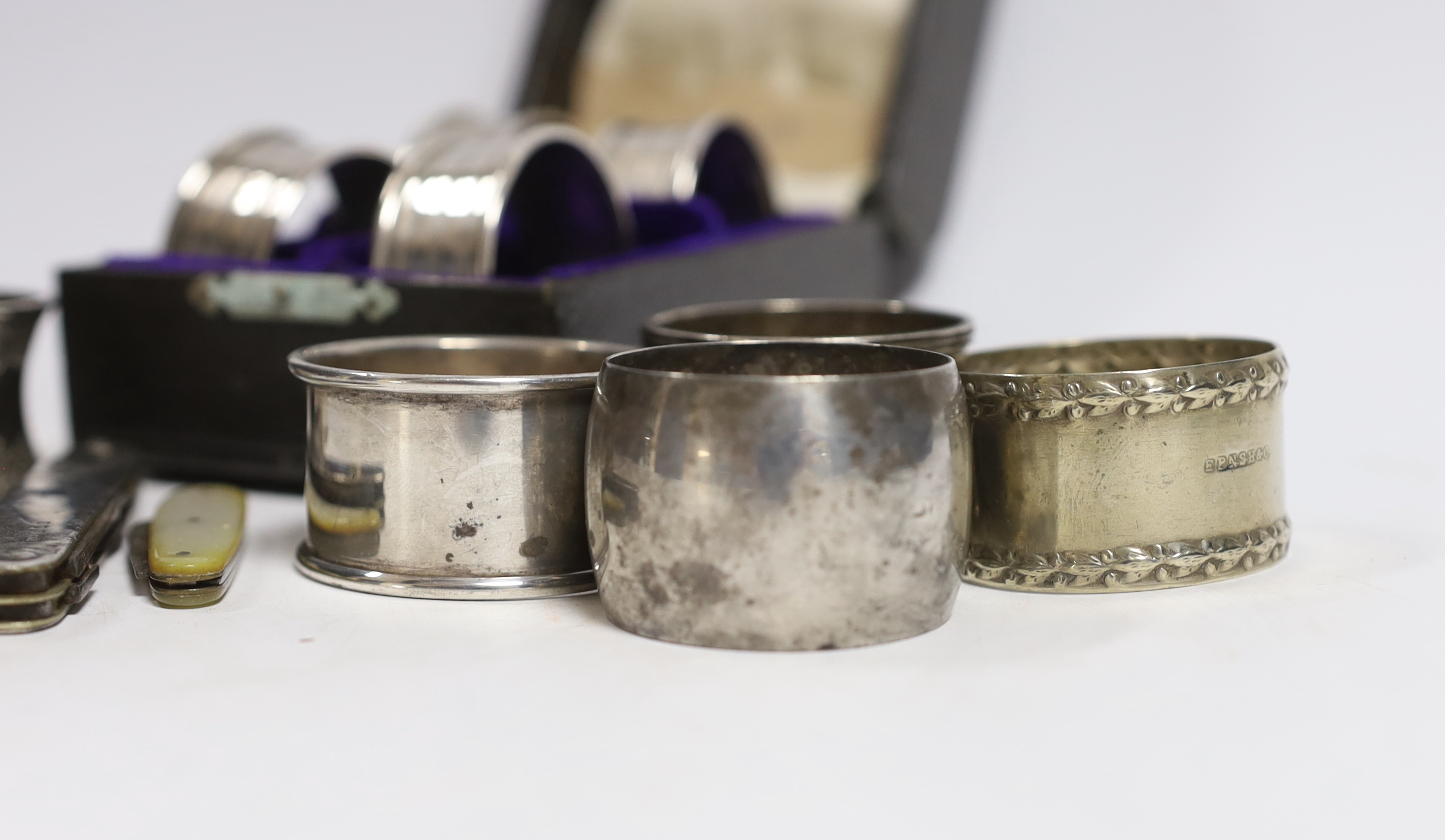 A cased set of four George V silver napkin rings, Rolason Brothers, Birmingham, 1920, together with five other assorted silver napkin rings, three plated napkin rings, two mother of pearl mounted fruit knives and a silve